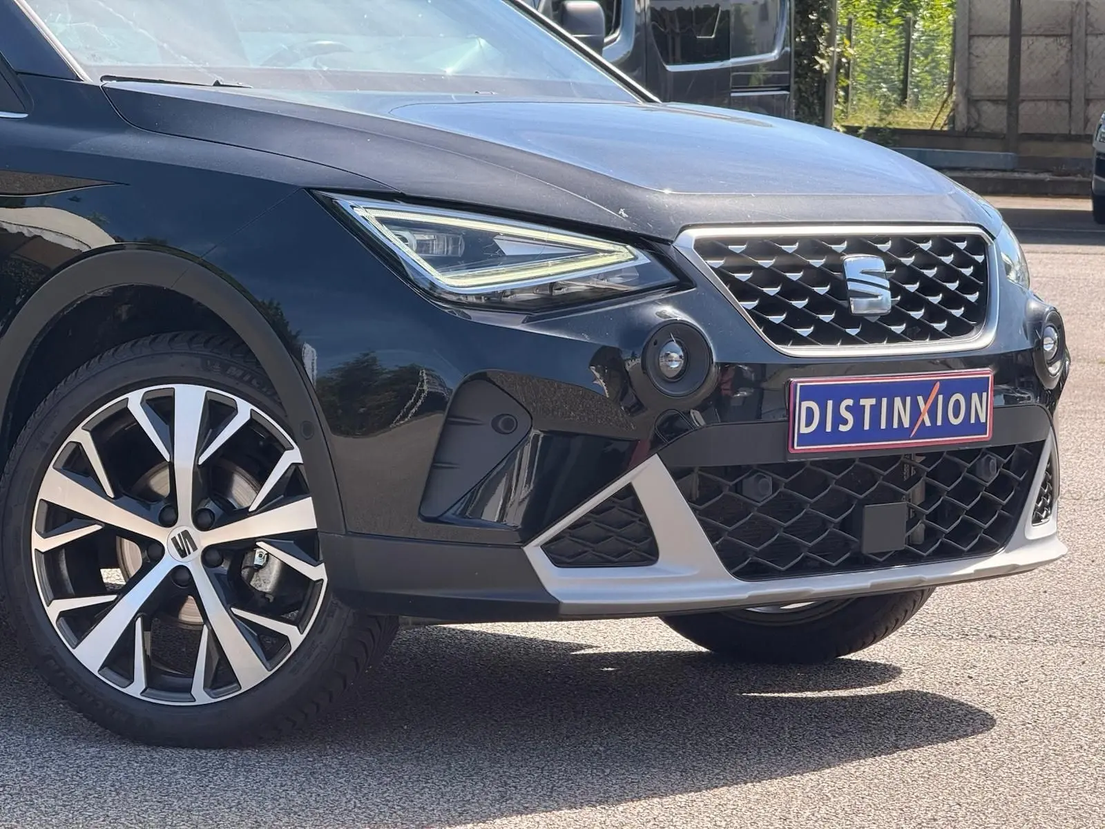 Vue 3/4 avant droite d'un SEAT Arona noir avec calandre chromée et jantes alliage distinctives.