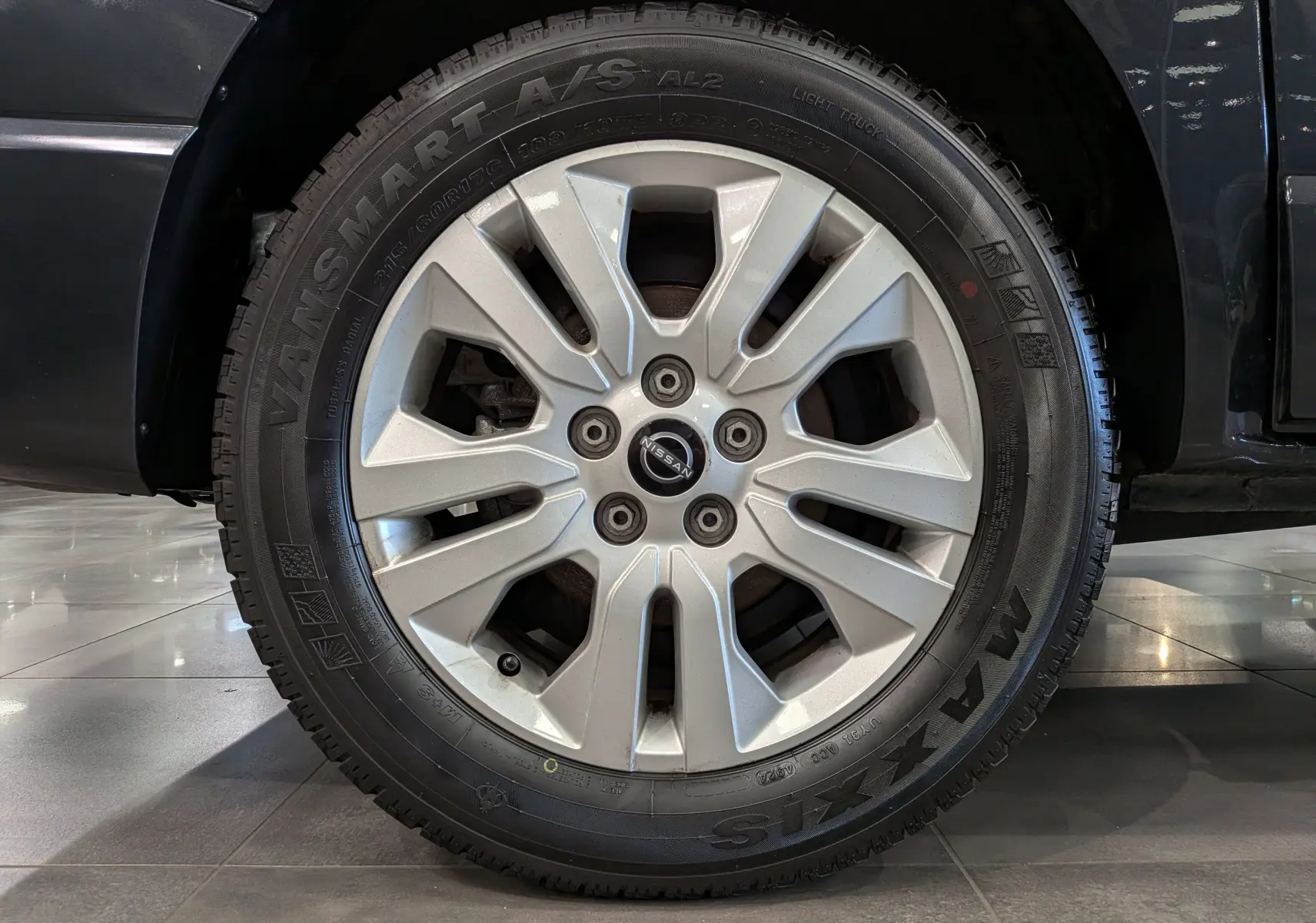Gros plan sur la roue avant droite du Nissan Primastar Combi gris comète, avec jante alliage et pneu Maxxis Vansmart A/S.