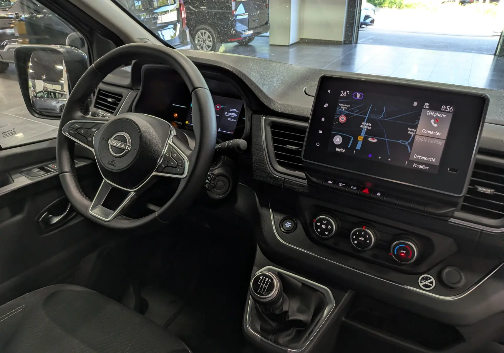 Vue intérieure côté conducteur du Nissan Primastar Combi gris, avec volant multifonction, écran tactile et boîte manuelle.
