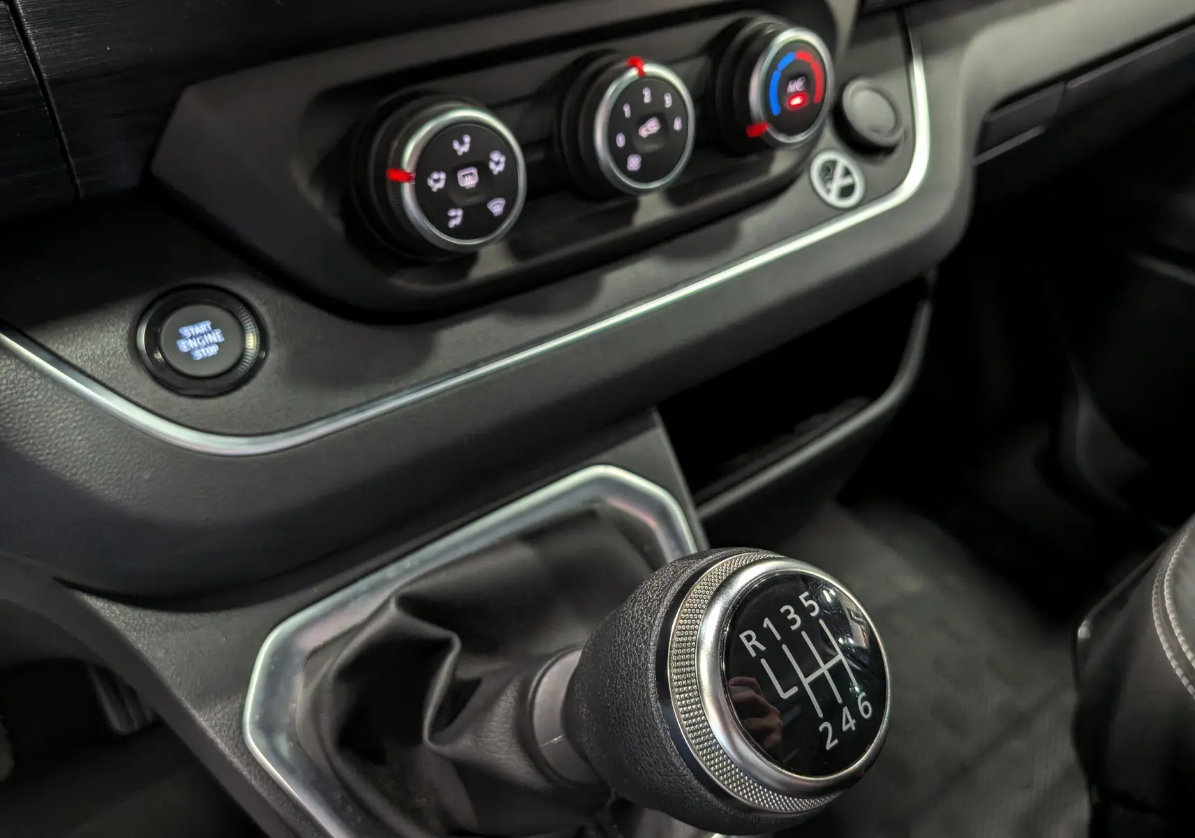 Gros plan sur la commande de boîte manuelle et les réglages de climatisation du Nissan Primastar Combi gris Comète 2025.