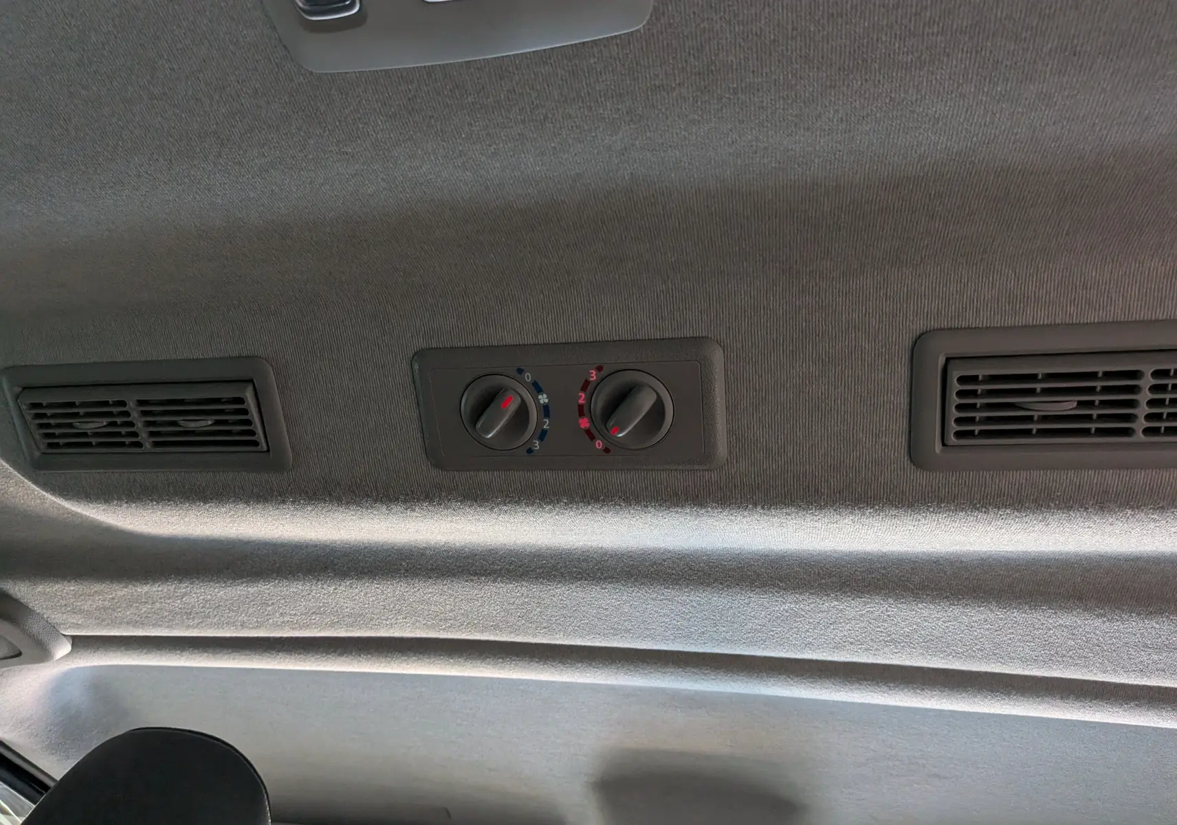 Vue intérieure du plafond du Nissan Primastar Combi gris, montrant les commandes de ventilation arrière et deux bouches d'aération.