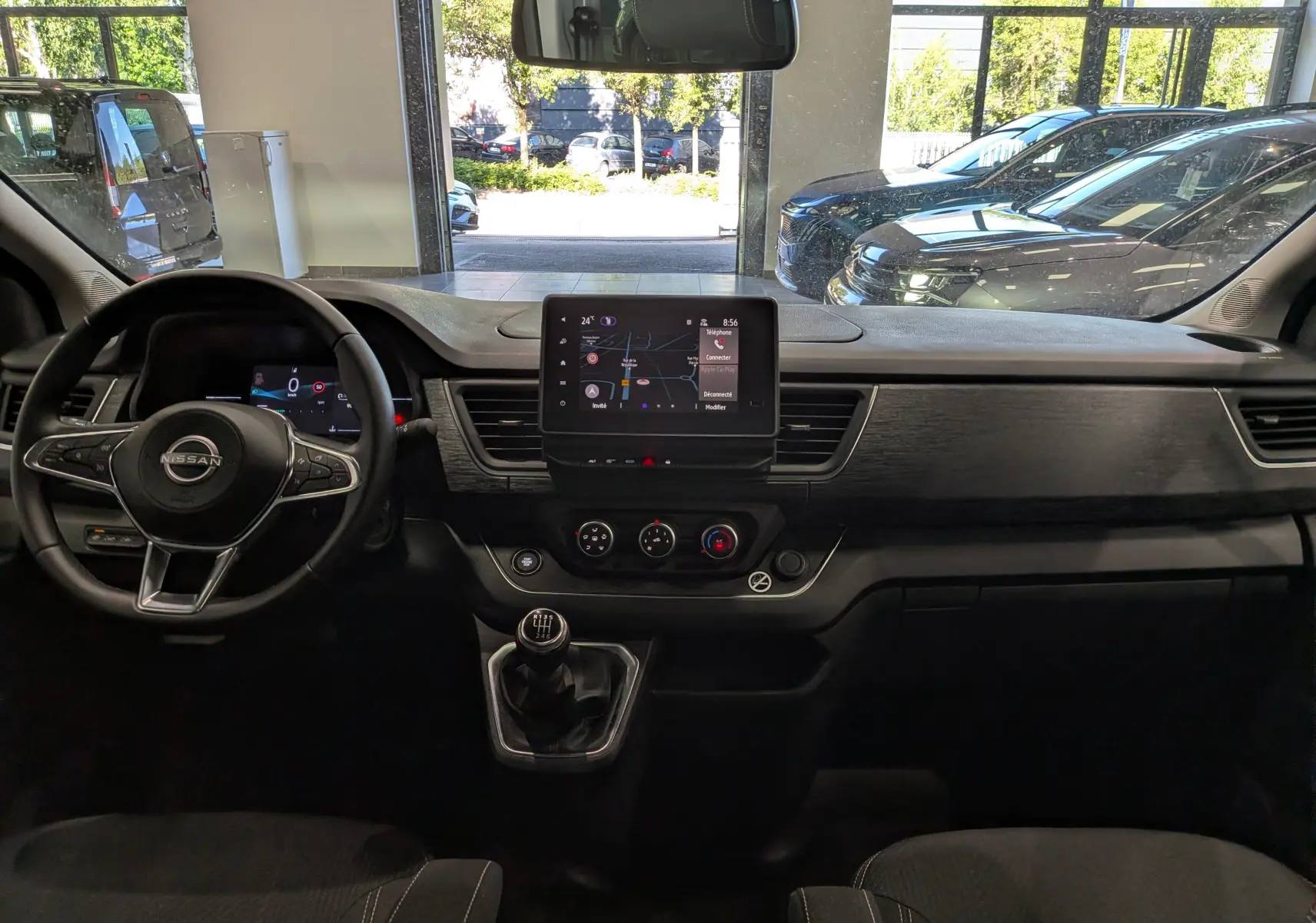 Vue intérieure avant du Nissan Primastar Combi 2025 avec tableau de bord noir, écran tactile central et boîte manuelle.