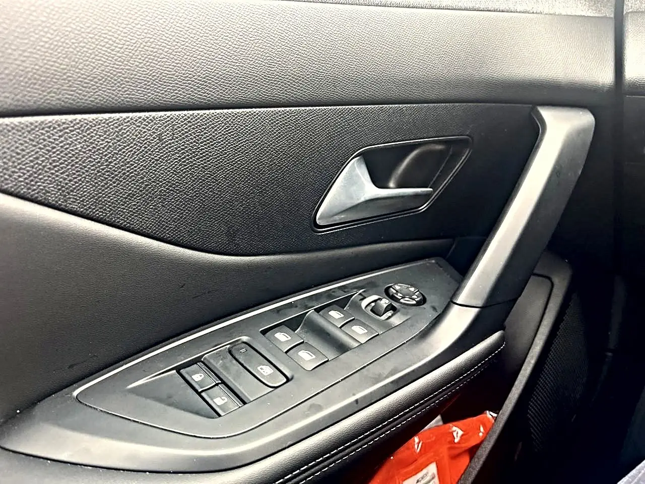 Gros plan sur la porte côté conducteur noire de la Peugeot 308 2025 avec commandes des vitres et poignée argentée.