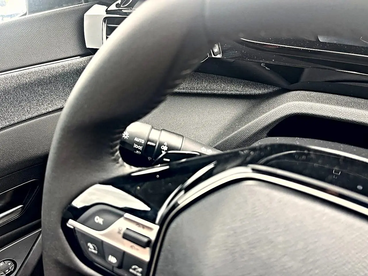 Vue rapprochée du volant noir multifonction et du tableau de bord intérieur gris de la Peugeot 308 2025.