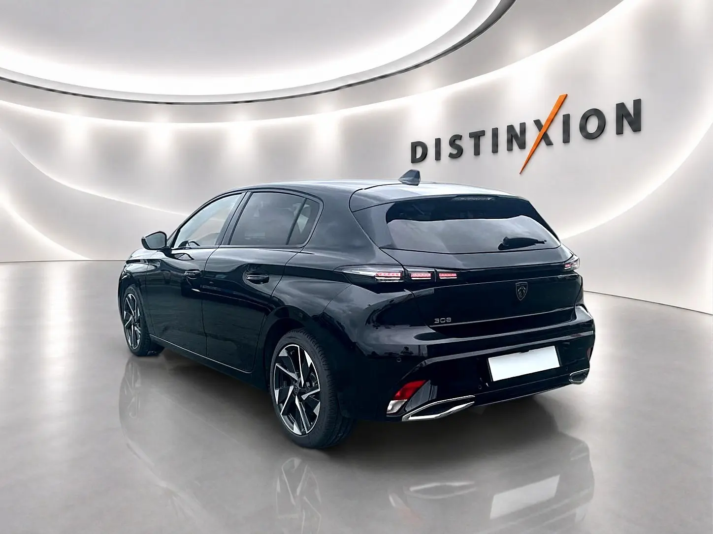 Peugeot 308 noire vue 3/4 arrière droit, jantes alu distinctives et feux arrière LED dans un showroom lumineux.