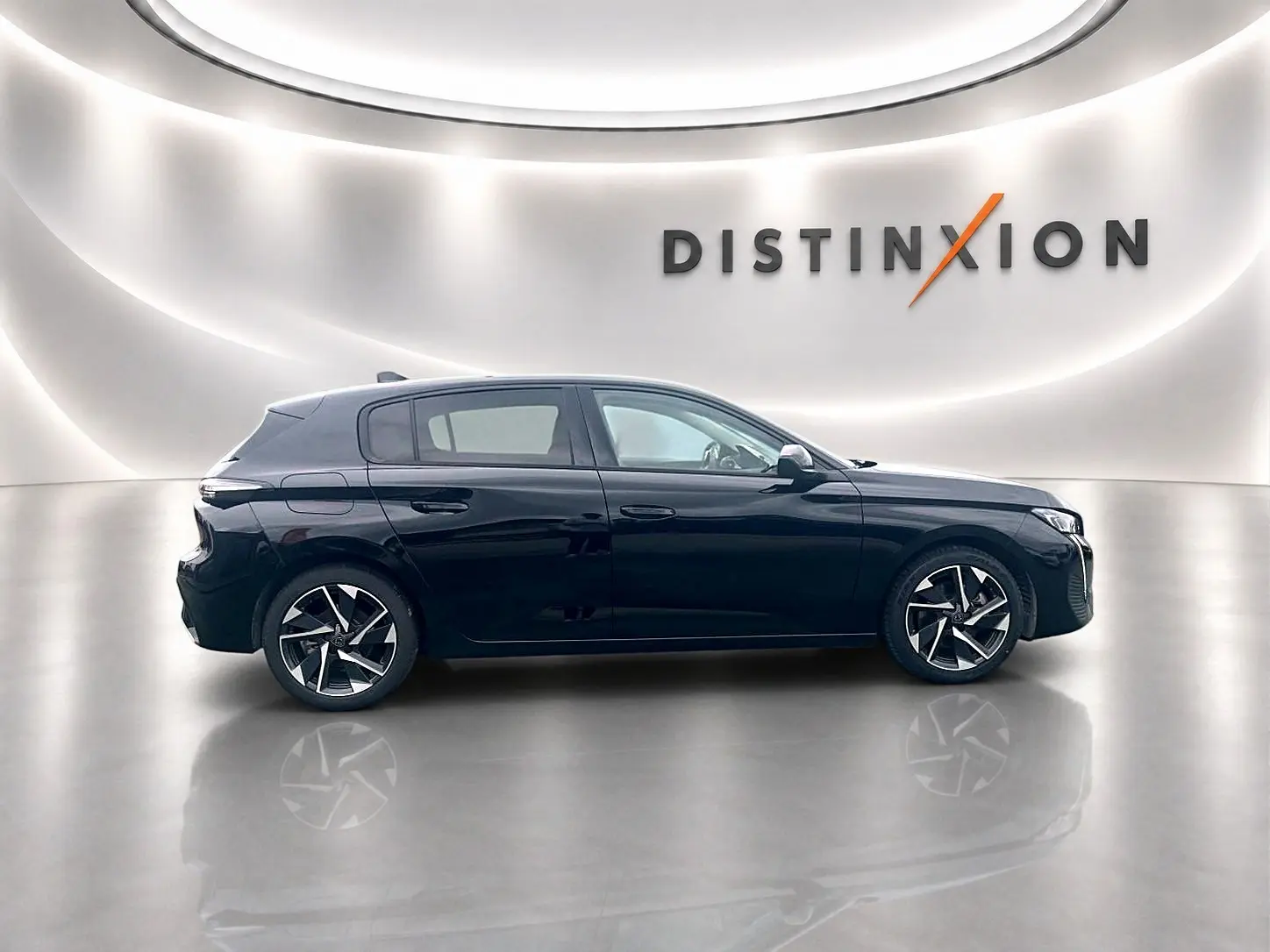 Profil côté gauche d'une Peugeot 308 noire 2025 avec jantes alu stylisées, dans un showroom lumineux "Distinxion".