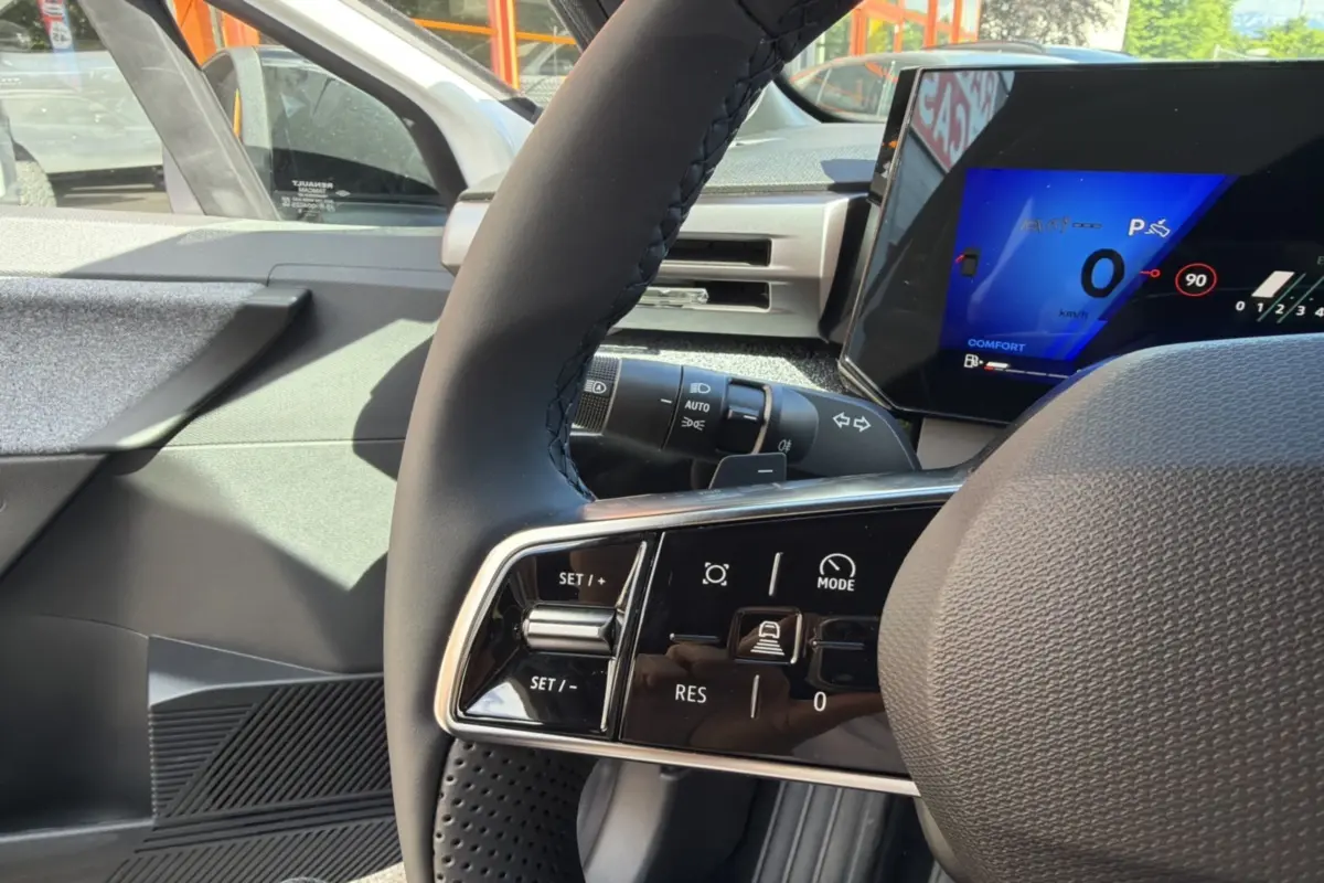 Gros plan sur le volant textile grainé et les commandes multifonctions d’une Renault Clio 6 TCE 115 EDC Techno.