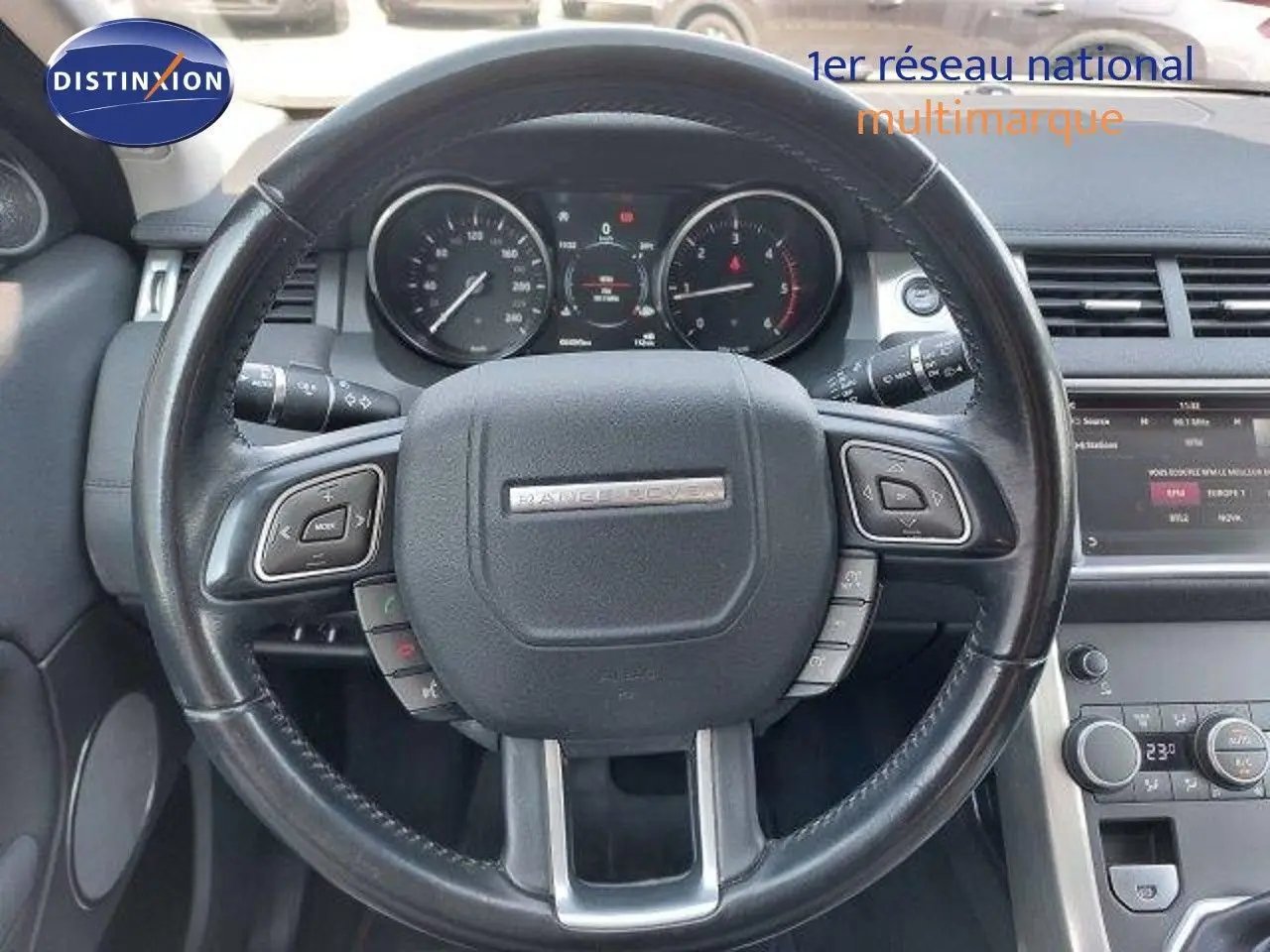 Vue rapprochée du volant noir du Range Rover Evoque blanc 2018 avec tableau de bord et commandes intégrées visibles.