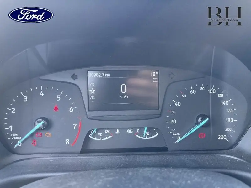 Vue rapprochée du tableau de bord de la Ford Fiesta 2021 avec écran multifonction et compteurs analogiques allumés.