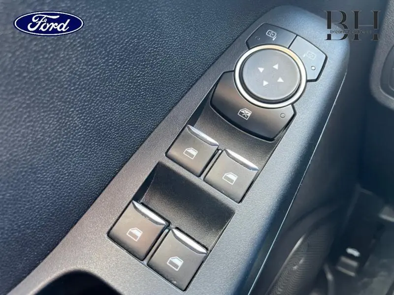 Gros plan sur les commandes des vitres électriques et réglage des rétroviseurs côté conducteur d'une Ford Fiesta gris Fashion Magnetic.