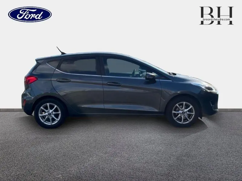 Profil droit d'une Ford Fiesta 1.1 75ch Titanium 5p en gris Fashion Gris Magnetic avec vitres arrière surteintées.