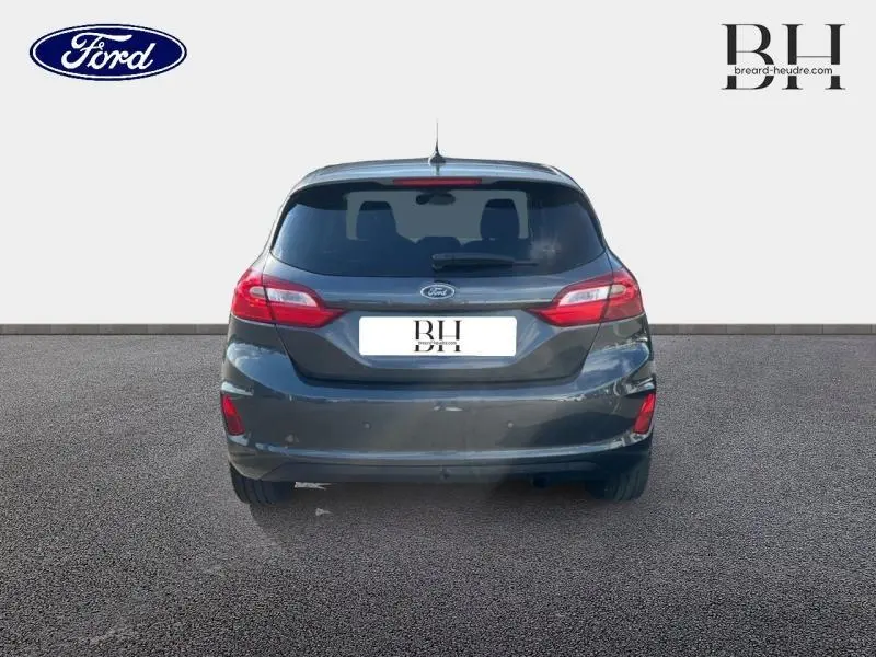 Vue arrière d'une Ford Fiesta 1.1 Titanium 2021 en gris Fashion Magnetic avec feux arrière LED et vitres surteintées.
