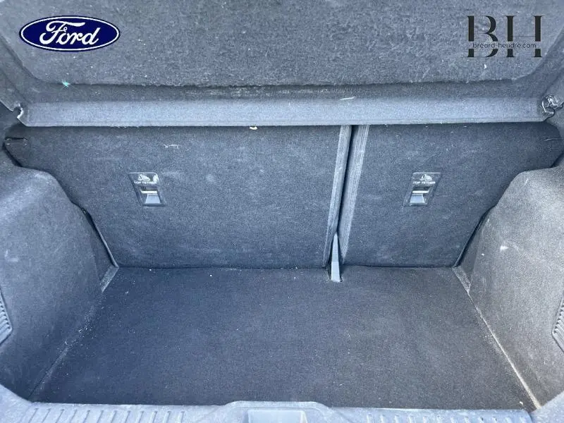 Coffre ouvert de la Ford Fiesta 1.1 75ch Titanium 2021 en Fashion Gris Magnetic, montrant l'espace de chargement vide et la banquette arrière rabattable.