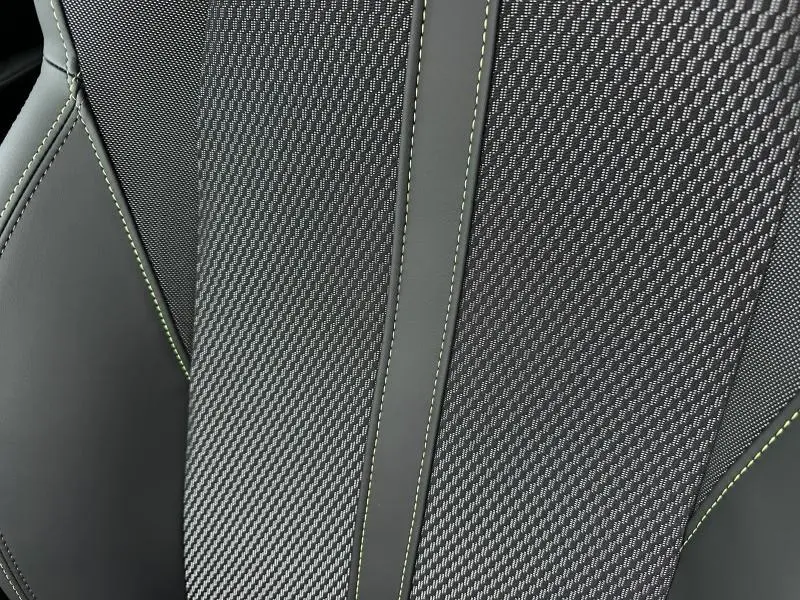 Gros plan sur la sellerie noire avec surpiqûres vertes de la Peugeot 208 Hybrid 110ch GT 2025.