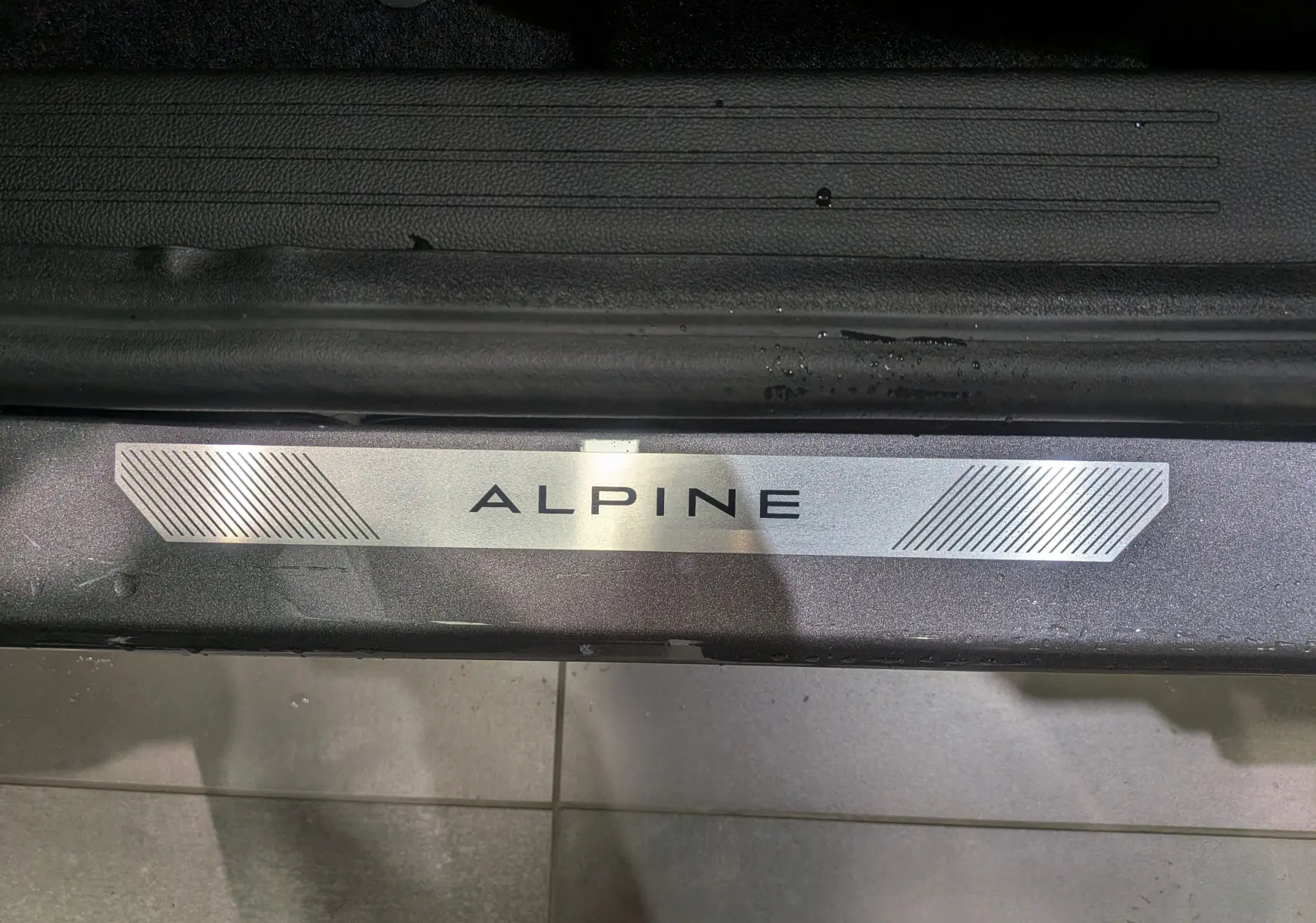 Gros plan sur la plaque de seuil de porte Alpine du Renault Symbioz gris Cassiopé, soulignant la finition Esprit Alpine.