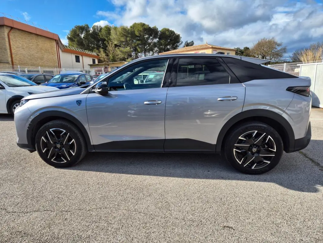 Vue de profil côté gauche d’un Peugeot 3008 Hybrid gris clair avec jantes alliage noires 19 pouces et toit noir.