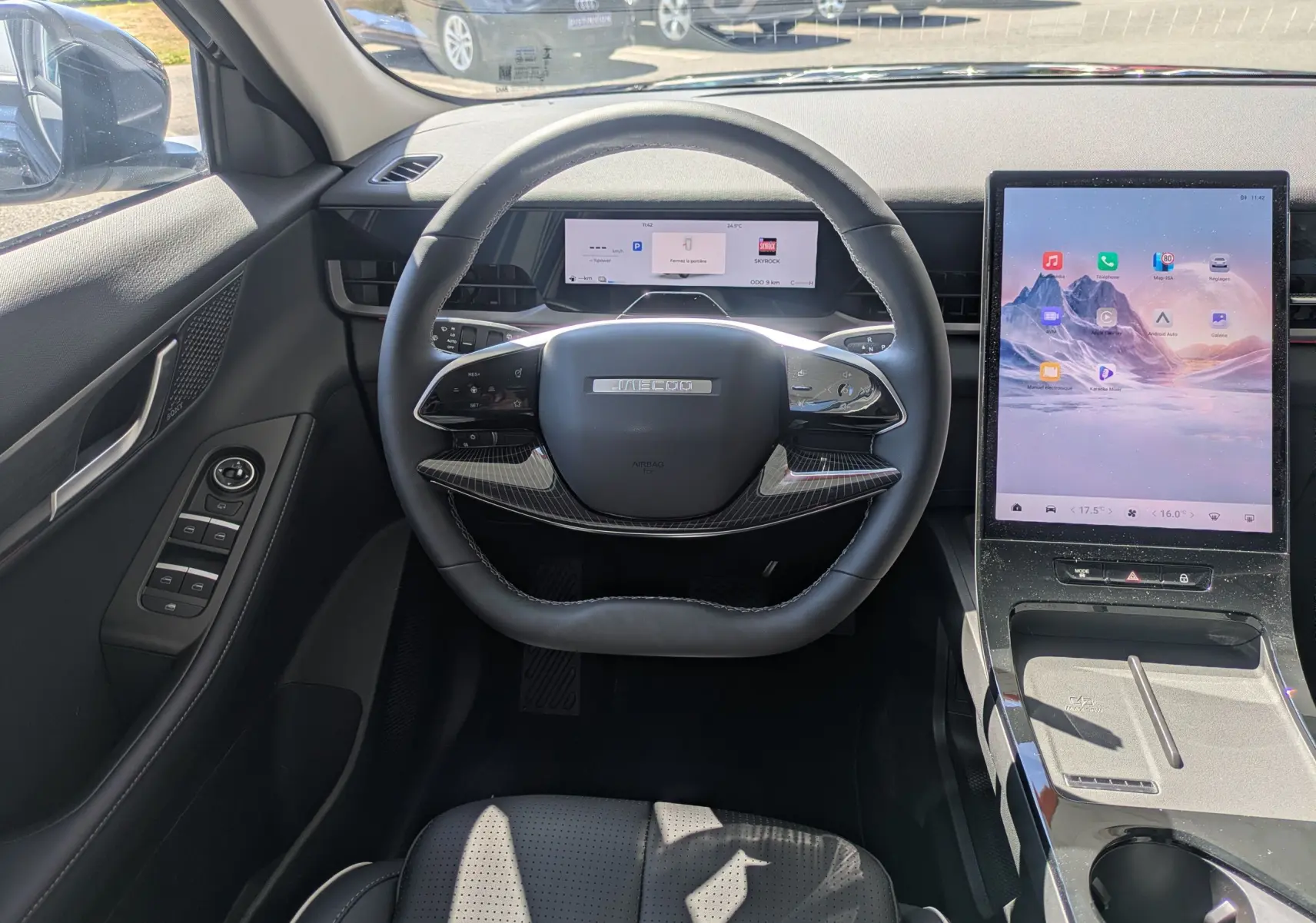 Vue intérieure centrée sur le volant noir carbone et le grand écran tactile vertical du tableau de bord du JAECOO J5.