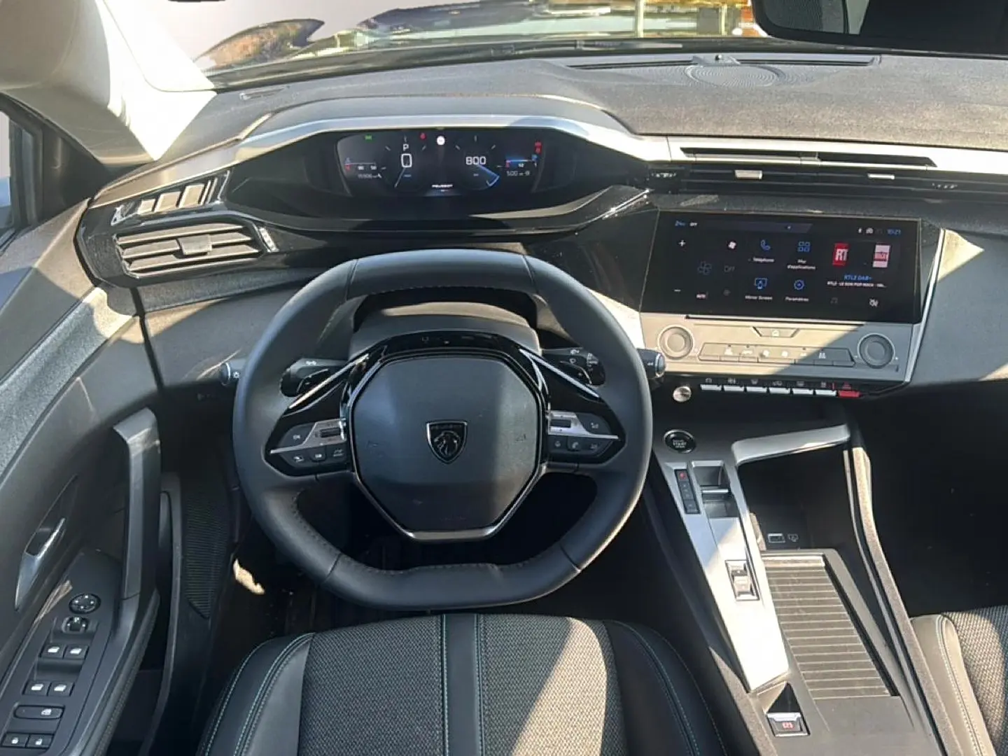 Vue intérieure frontale du poste de conduite de la Peugeot 308 gris artense, avec volant multifonction et écran tactile.