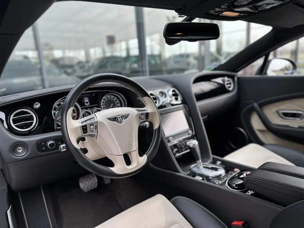 Intérieur de la Bentley Continental GT Mulliner 2013, vue côté conducteur, volant cuir bicolore noir et beige avec tableau de bord élégant.