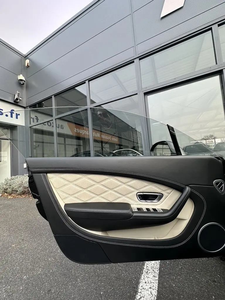 Détail de la porte côté gauche en cuir noir et beige matelassé de la Bentley Continental GT 4.0 V8 Mulliner 2013.