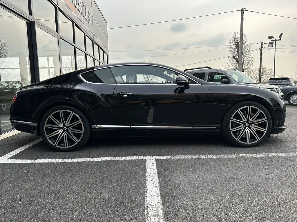 Vue de profil côté gauche d'une Bentley Continental GT noire 4.0 V8 Mulliner avec jantes alliage distinctives.