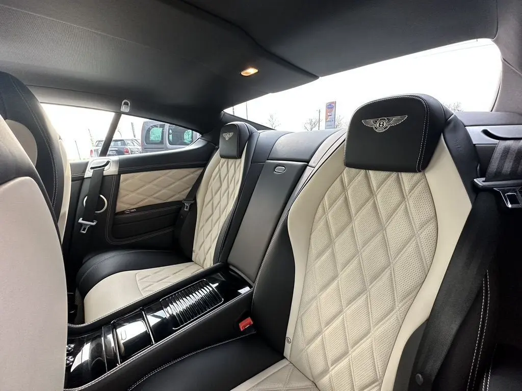 Vue intérieure arrière droite de la Bentley Continental GT 2013 noire, sièges cuir beige matelassé avec logo Mulliner brodé.