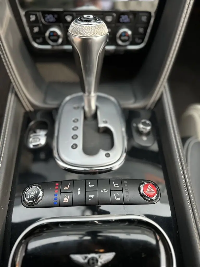 Gros plan sur la console centrale noire de la Bentley Continental GT 4.0 V8 Mulliner 2013 avec levier de vitesse automatique et commandes intégrées.