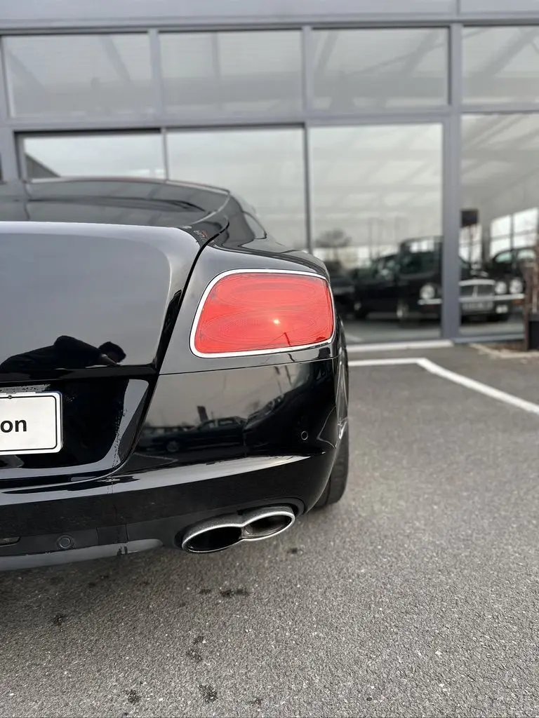 Vue arrière droite d'une Bentley Continental GT noire 4.0 V8 Mulliner de 2013, avec feu arrière et double sortie d'échappement visibles.