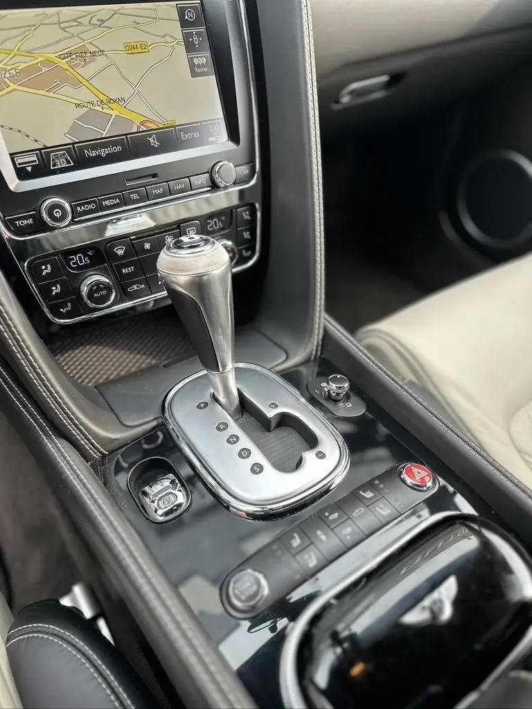 Gros plan sur la console centrale noire de la Bentley Continental GT 4.0 V8 Mulliner 2013 avec levier de boîte auto et écran navigation.