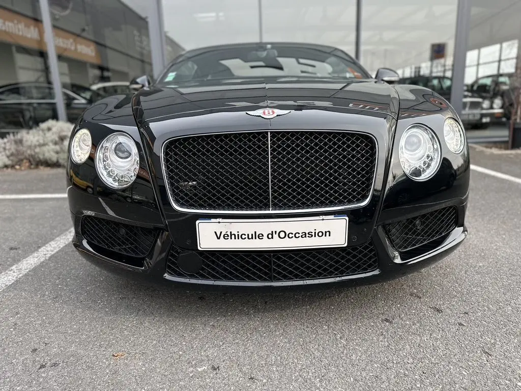 Vue frontale rapprochée de la Bentley Continental GT Mulliner noire de 2013 avec sa calandre distinctive et ses phares ronds.