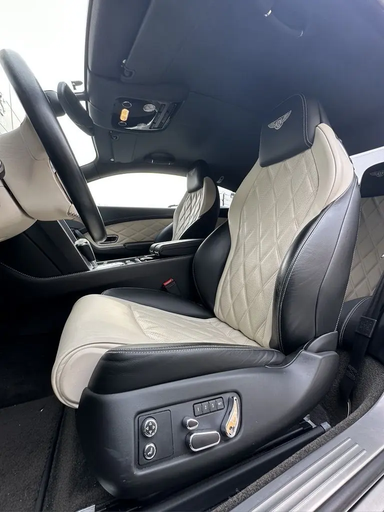 Intérieur de la Bentley Continental GT 2013 vue côté gauche, sièges cuir bicolore beige et noir avec logo Mulliner brodé.