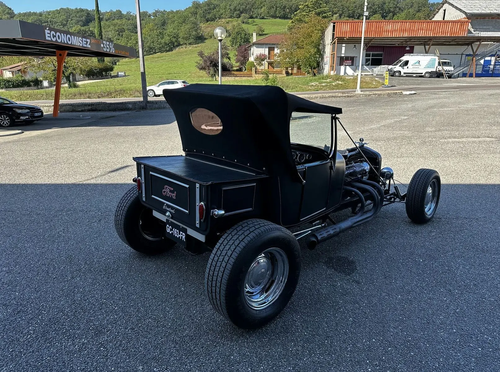 Vue 3/4 arrière droite d'une Ford T Hot Rod V8 noire décapotable avec moteur apparent et jantes chromées.