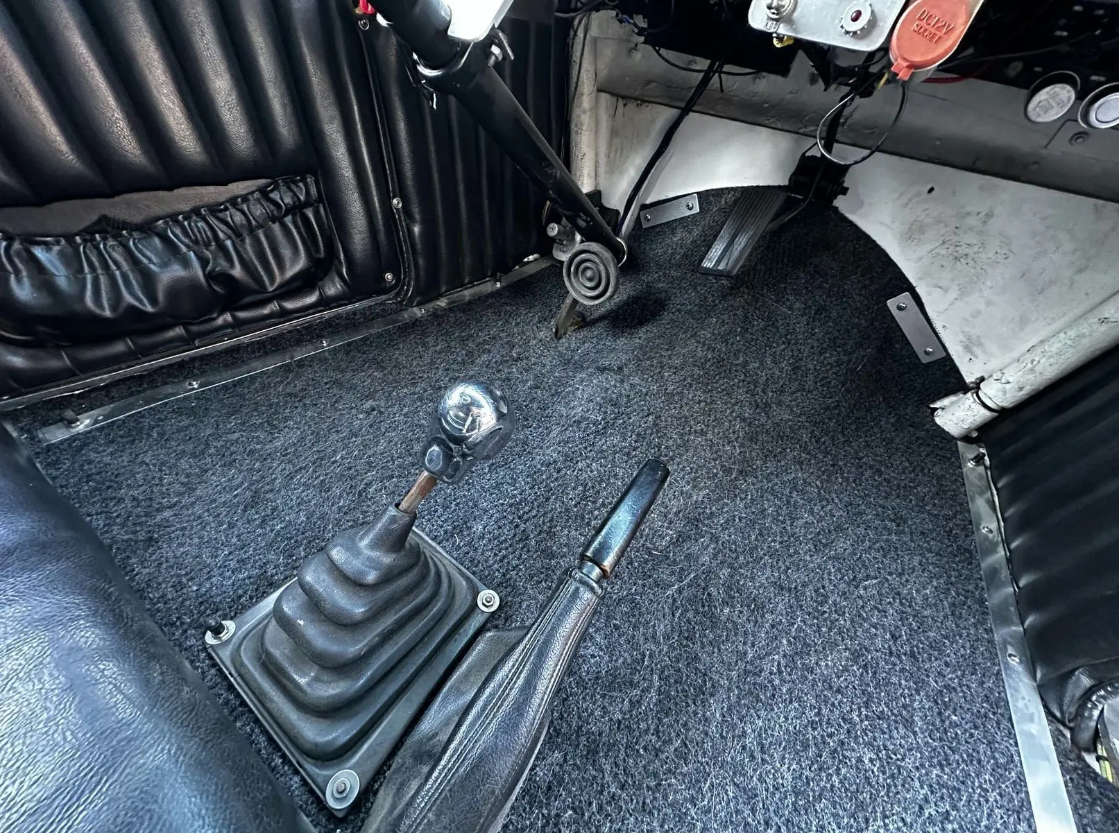 Vue rapprochée du levier de vitesse chromé tête de mort et frein à main cuir dans l'habitacle noir du Ford T Hot Rod 1923.