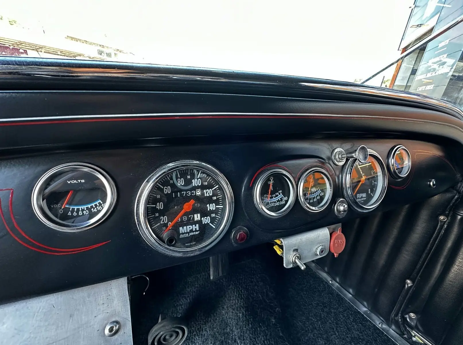 Tableau de bord noir du Ford T Hot Rod 1923 avec compte-tours, voltmètre et compteur de vitesse en vue rapprochée.