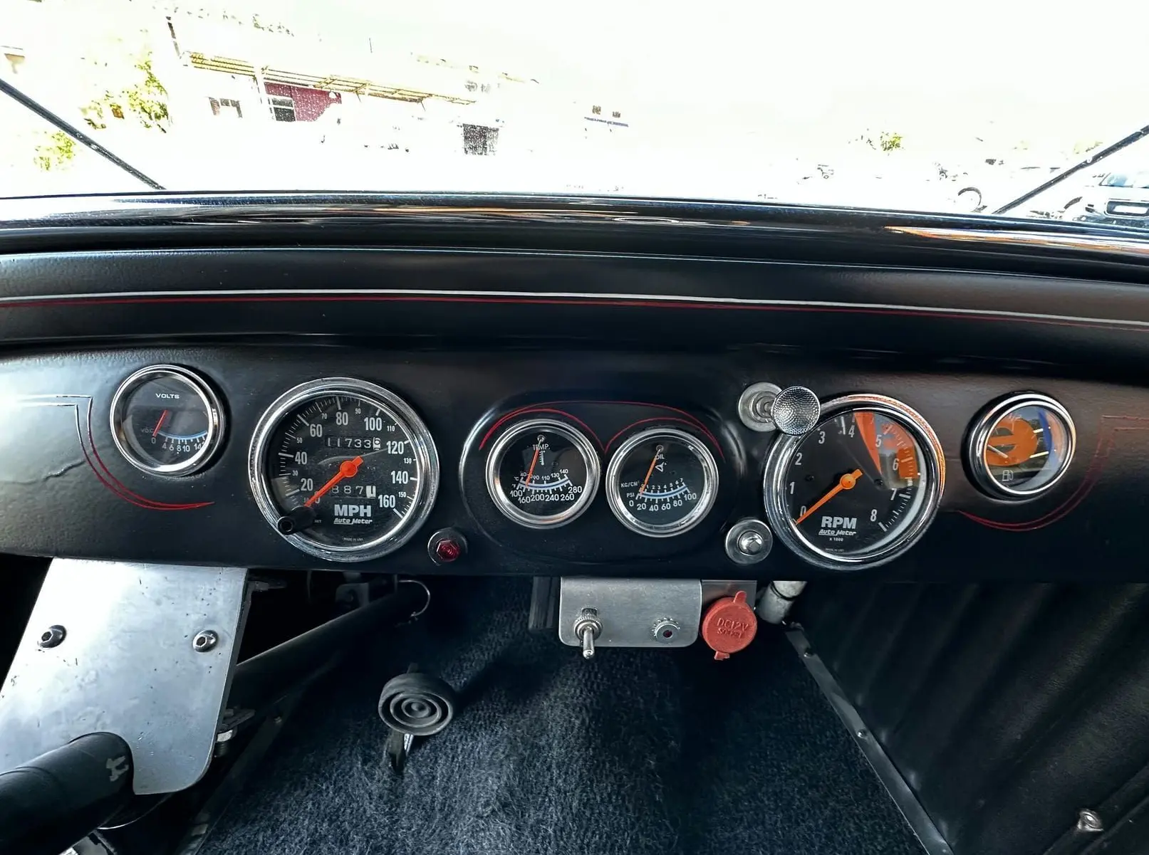 Tableau de bord noir du Ford T Hot Rod V8 1923 avec compte-tours, compteur de vitesse et indicateurs ronds chromés.