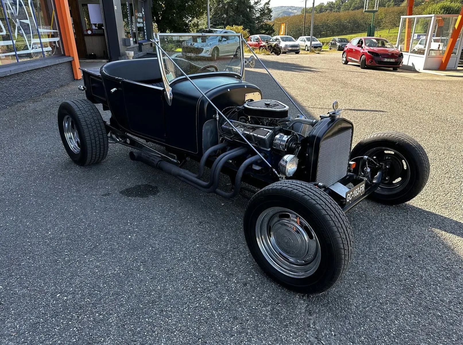 Ford T Hot Rod V8 noir vue 3/4 avant droit, moteur apparent et carrosserie décapotable avec liserés faits main.