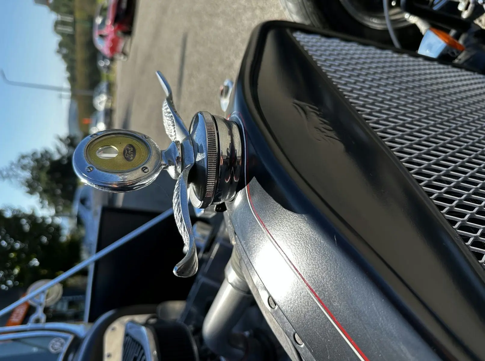 Gros plan sur le bouchon de radiateur chromé avec logo Ford, liseré rouge et calandre noire du Ford T Hot Rod 1923.