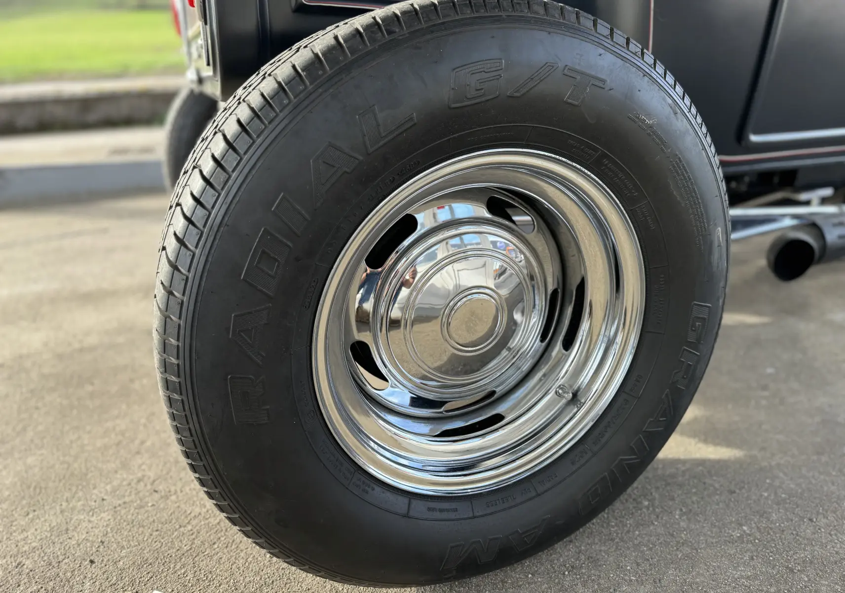 Gros plan sur la roue arrière droite chromée du Ford T Hot Rod noir de 1923 avec pneus Radial G/T.