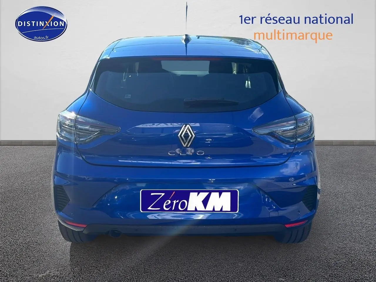 Vue arrière d'une Renault Clio V bleu iron avec feux arrière LED et becquet intégré sur fond neutre.