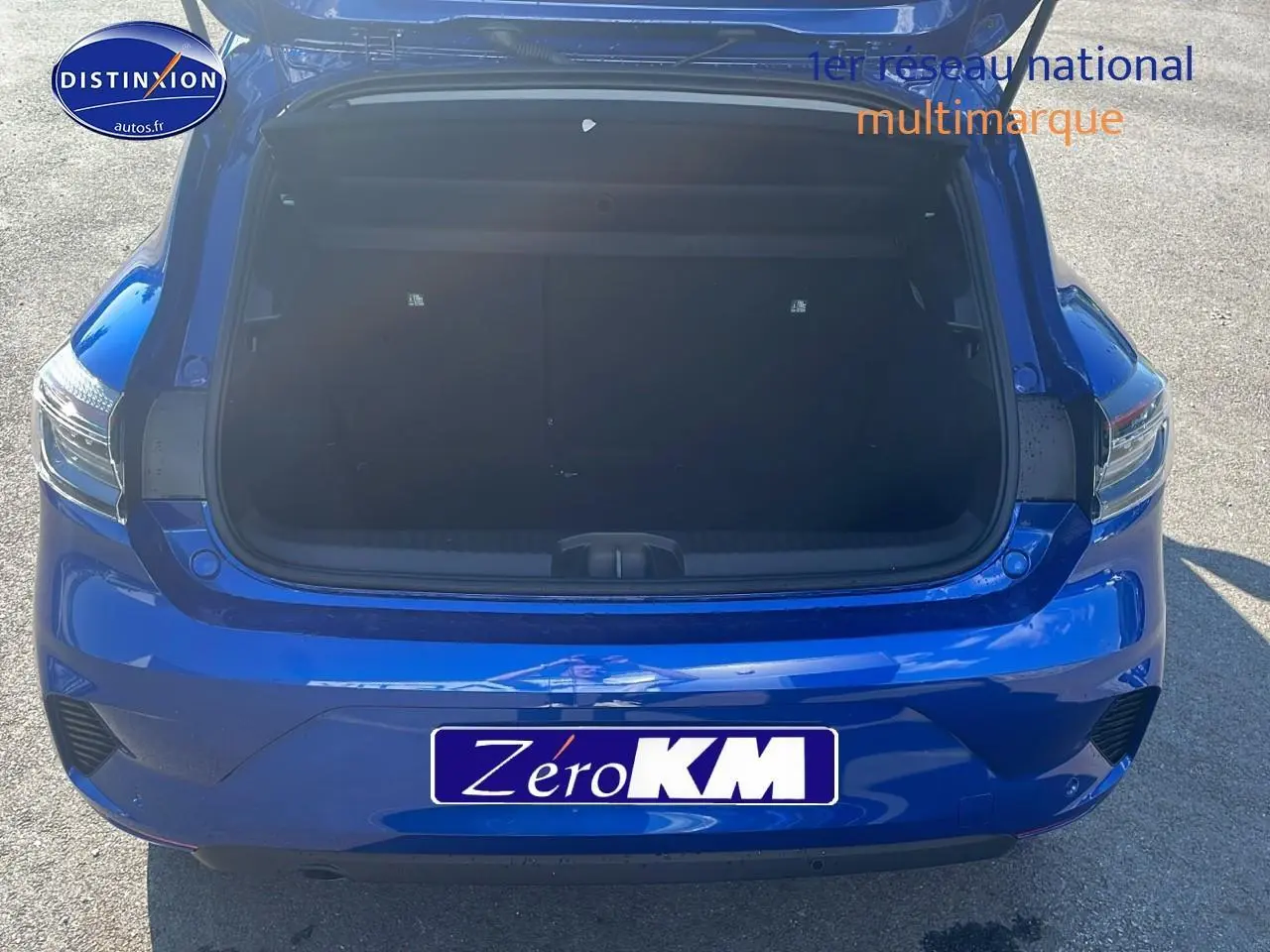 Coffre ouvert vu de l'arrière d'une Renault Clio V bleu iron, avec feux arrière LED et bouclier couleur carrosserie.