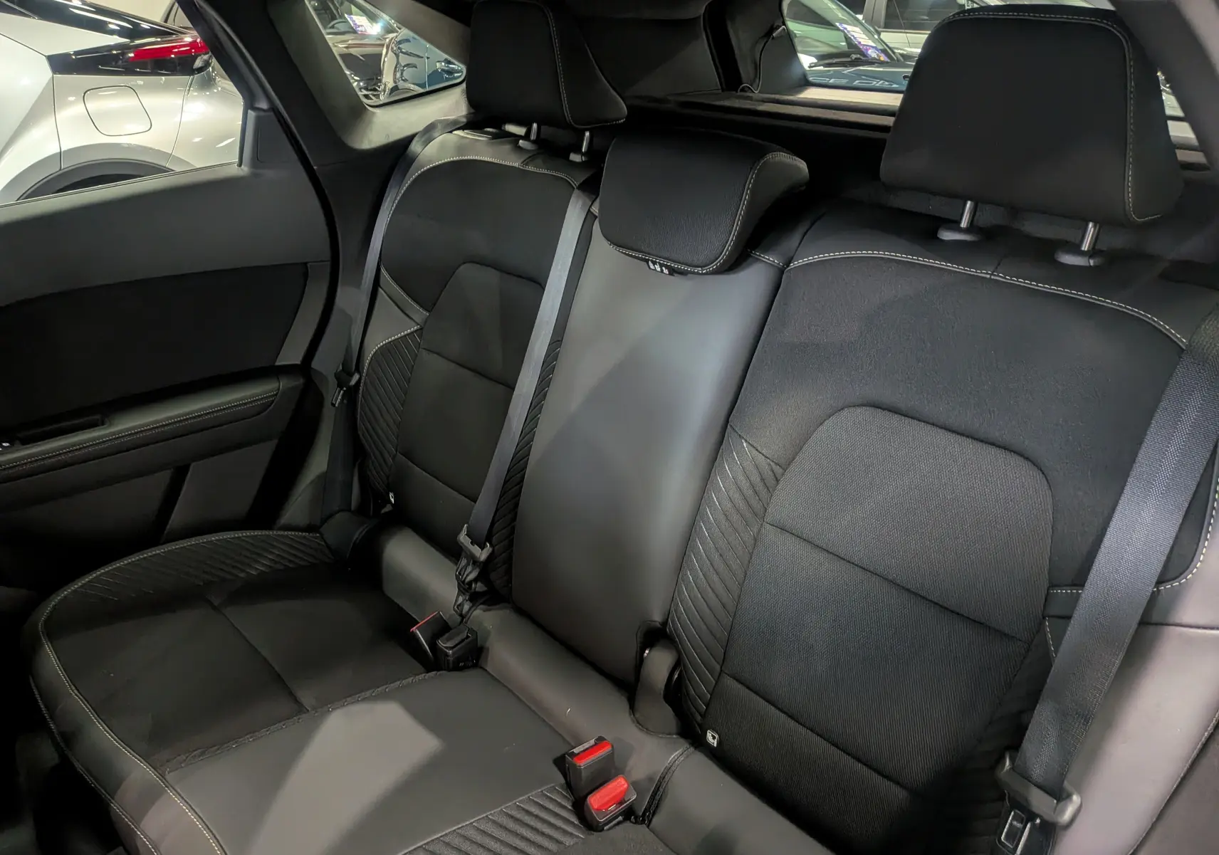 Vue intérieure arrière des sièges noirs en cuir et tissu du Renault Symbioz E-Tech 2025, avec ceinture de sécurité visible.