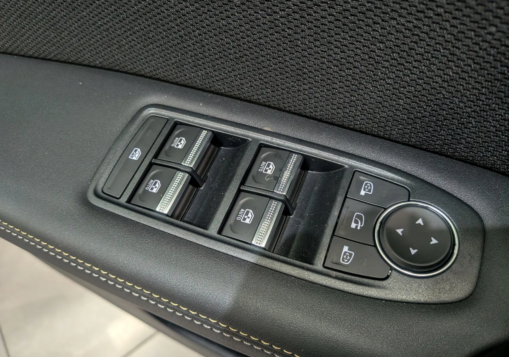 Panneau de commandes des vitres électriques et rétroviseurs sur la porte intérieure d'une Renault Symbioz gris Cassiopé.