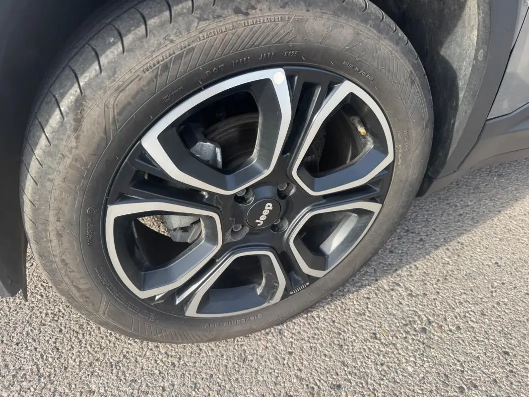 Gros plan sur la jante alliage noire et argentée de 18 pouces du Jeep Avenger gris, avec logo Jeep au centre.