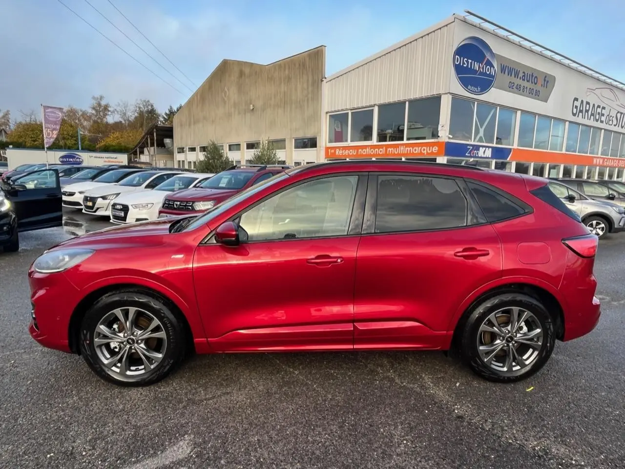 Vue latérale gauche d'un Ford Kuga 1.5 EcoBoost ST-Line rouge Lucifer avec vitres arrière surteintées et jantes alliage 18 pouces.