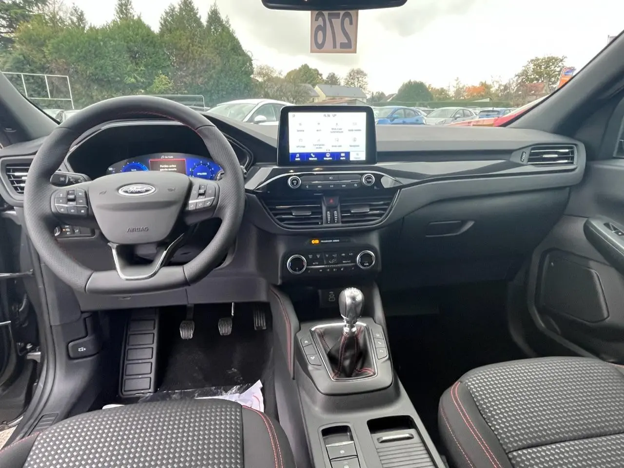 Vue intérieure avant du Ford Kuga 1.5 EcoBoost 2022, tableau de bord noir avec écran tactile et volant multifonctions.
