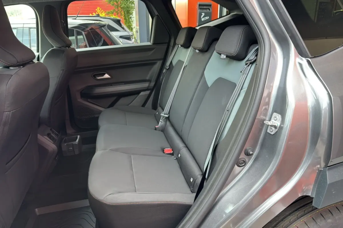 Vue côté droit sur la banquette arrière grise du Dacia Bigster 2026, avec portières ouvertes et ceinture de sécurité visible.