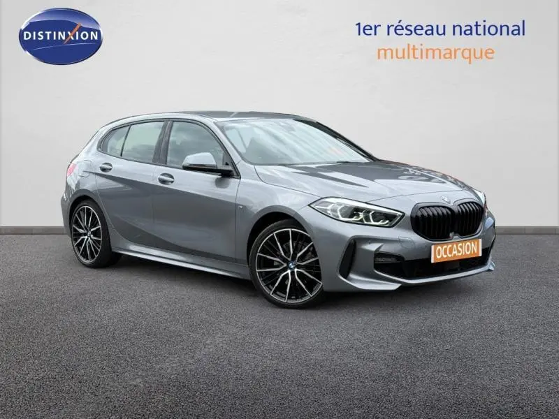 BMW Série 1 118dA M Sport gris métallisé vue 3/4 avant avec jantes alliage et calandre noire distinctive.