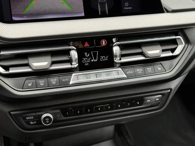 Vue rapprochée du tableau de bord noir de la BMW Série 1 118dA 2022, avec commandes climatisation et écran digital.
