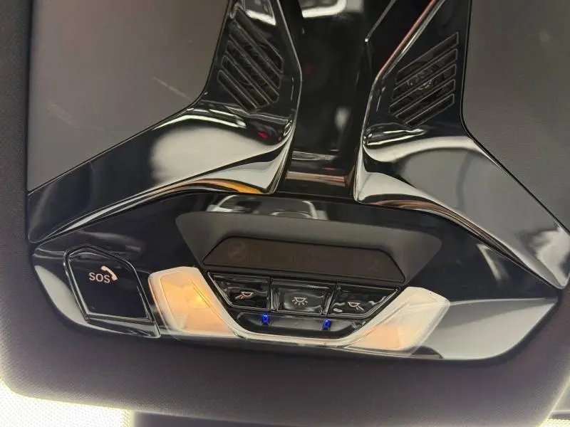 Vue en contre-plongée du plafonnier noir brillant de la BMW Série 1 118dA avec boutons d'éclairage et alerte SOS.