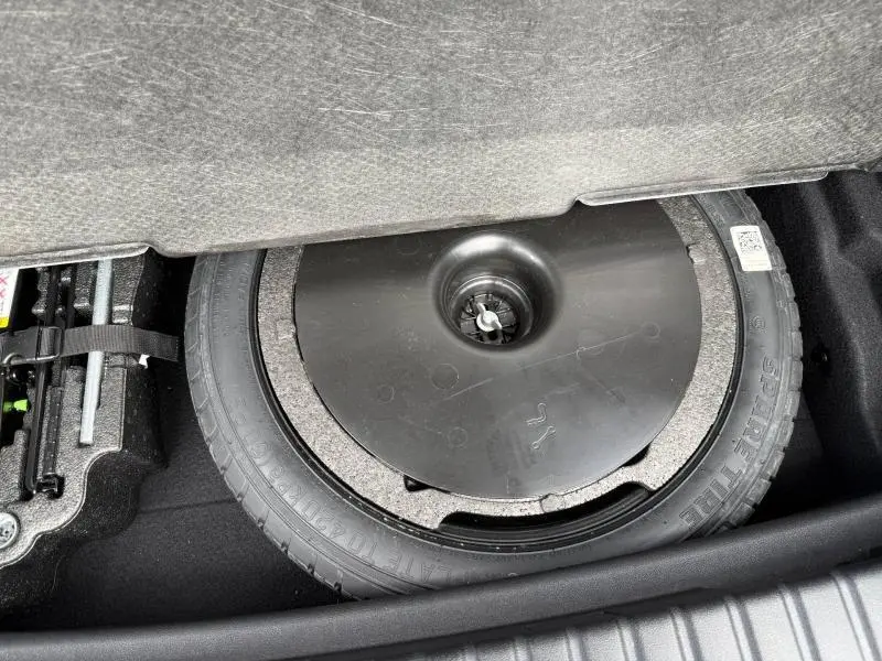 Vue rapprochée de la roue de secours et du kit de réparation dans le coffre d'une BMW Série 1 118dA 2022.